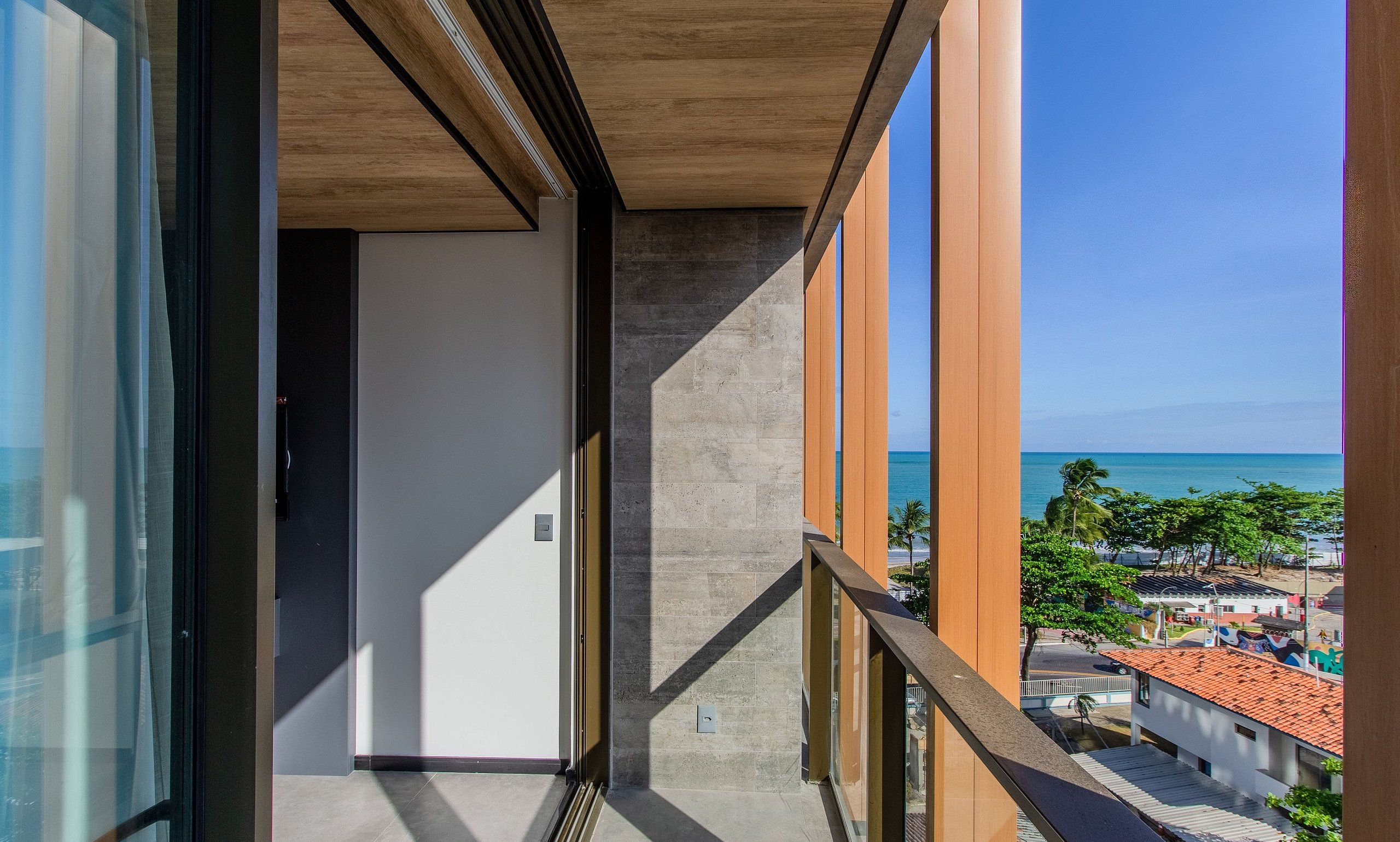 A balcony with a view of the ocean and a coastal town.