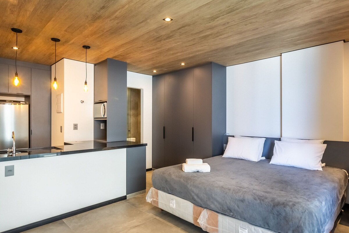 Ein modernes Schlafzimmer mit einem großen Bett, einem integrierten Schreibtisch und einem Spiegel.
