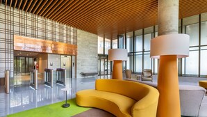 A modern lobby with a curved yellow sofa, a green carpet, and a wooden ceiling. - NWTs - Estúdios com Vista Lateral Mar (Maceió)