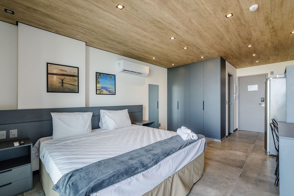 Ein modernes Hotelzimmer mit einem großen Bett, Nachttischen, einem Schreibtisch und einem Kleiderschrank.