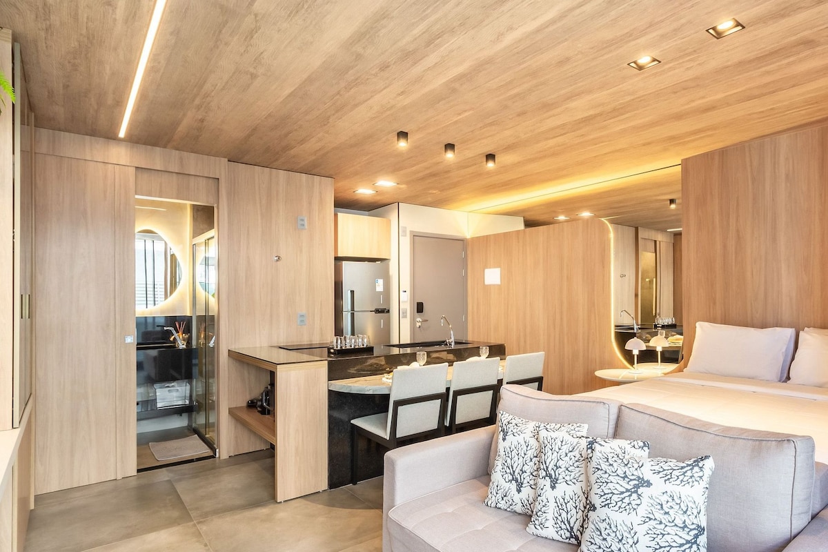 Un dormitorio moderno con una cama grande, un área de descanso y una kitchenette.
