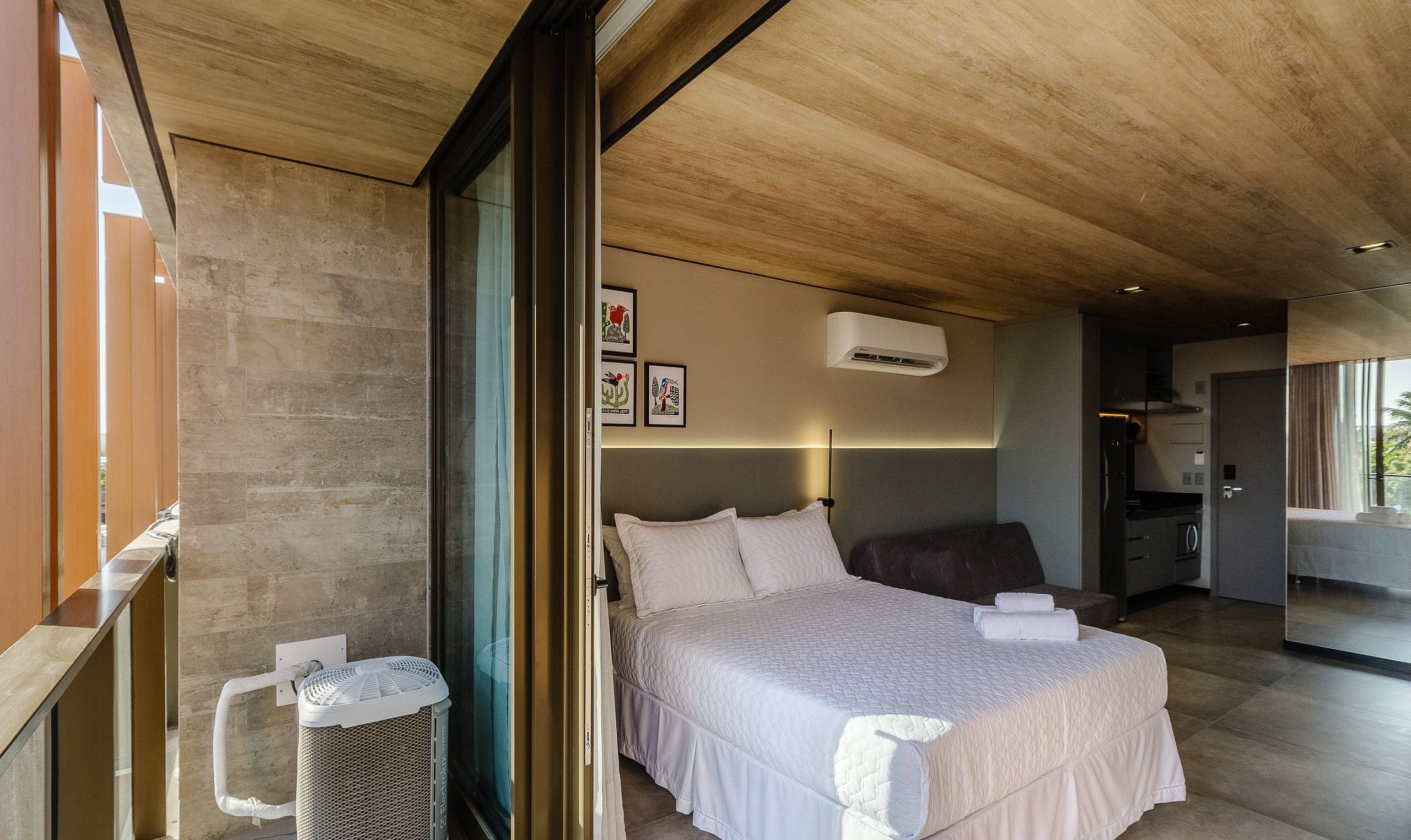 Une chambre moderne avec un grand lit, un radiateur près du lit et une vue sur la pièce adjacente.