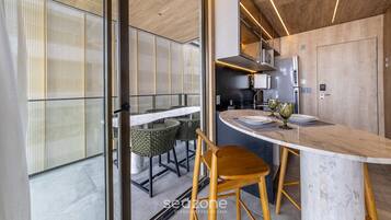 Una cocina moderna con encimera de mármol, electrodomésticos de acero inoxidable y un comedor con sillas de mimbre.