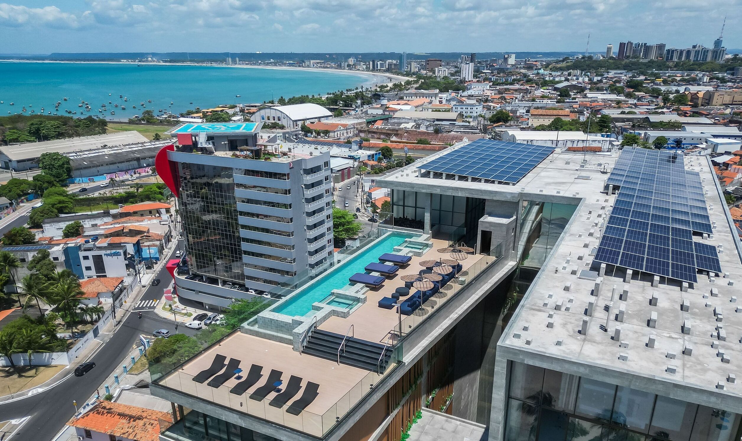 Um edifício alto com piscina no terraço e painéis solares.