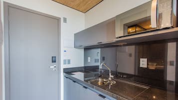 A modern kitchen with a black countertop, stainless steel sink, and a built-in oven.