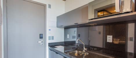 Cozinha moderna com bancada preta, pia de aço inoxidável e forno embutido.
