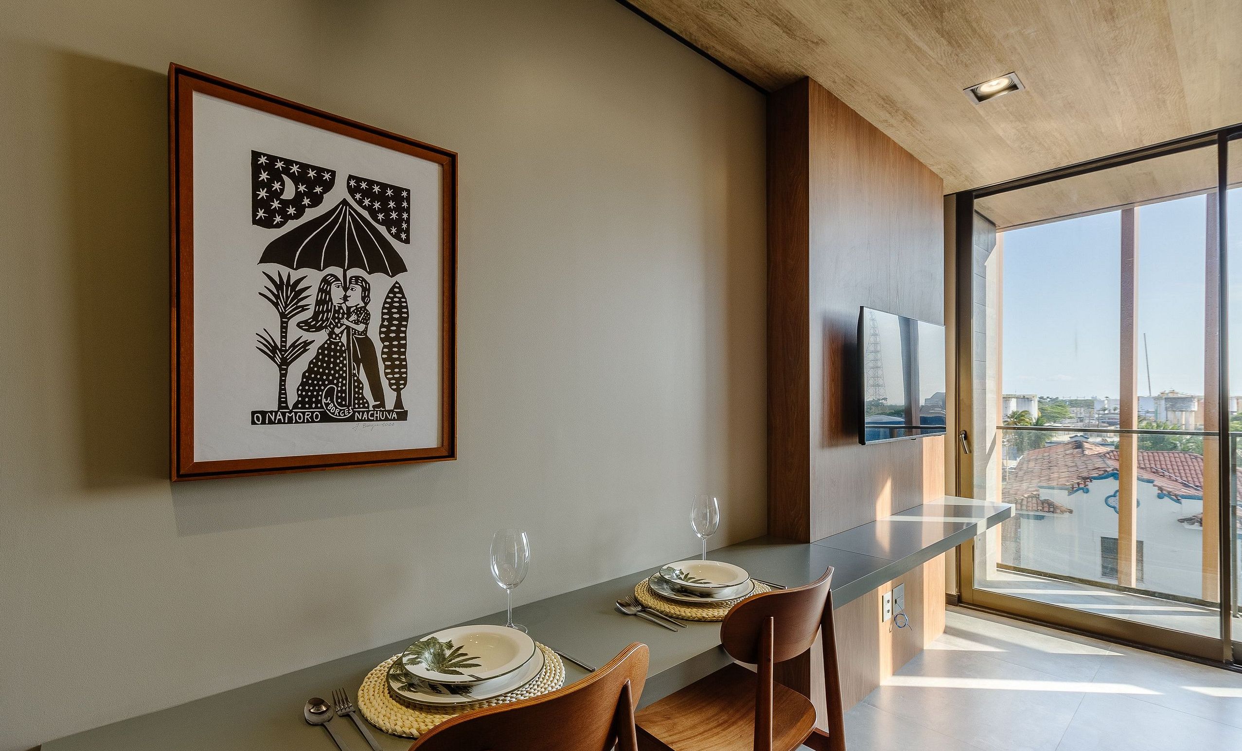 Un'area pranzo con un tavolo lungo, sedie e un'opera d'arte incorniciata appesa al muro.