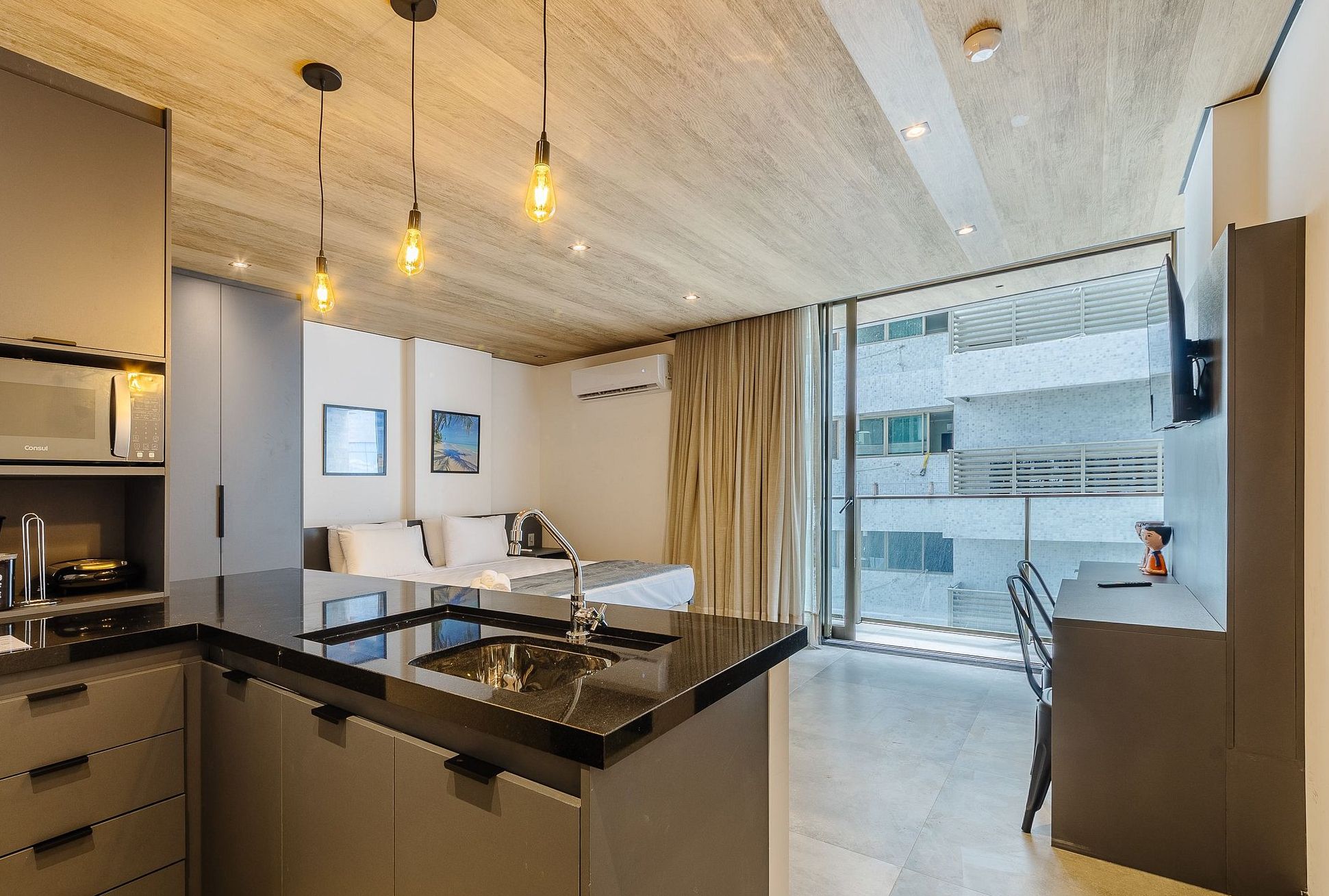 Una cocina moderna con una isla central, iluminación colgante y vistas a la ciudad.