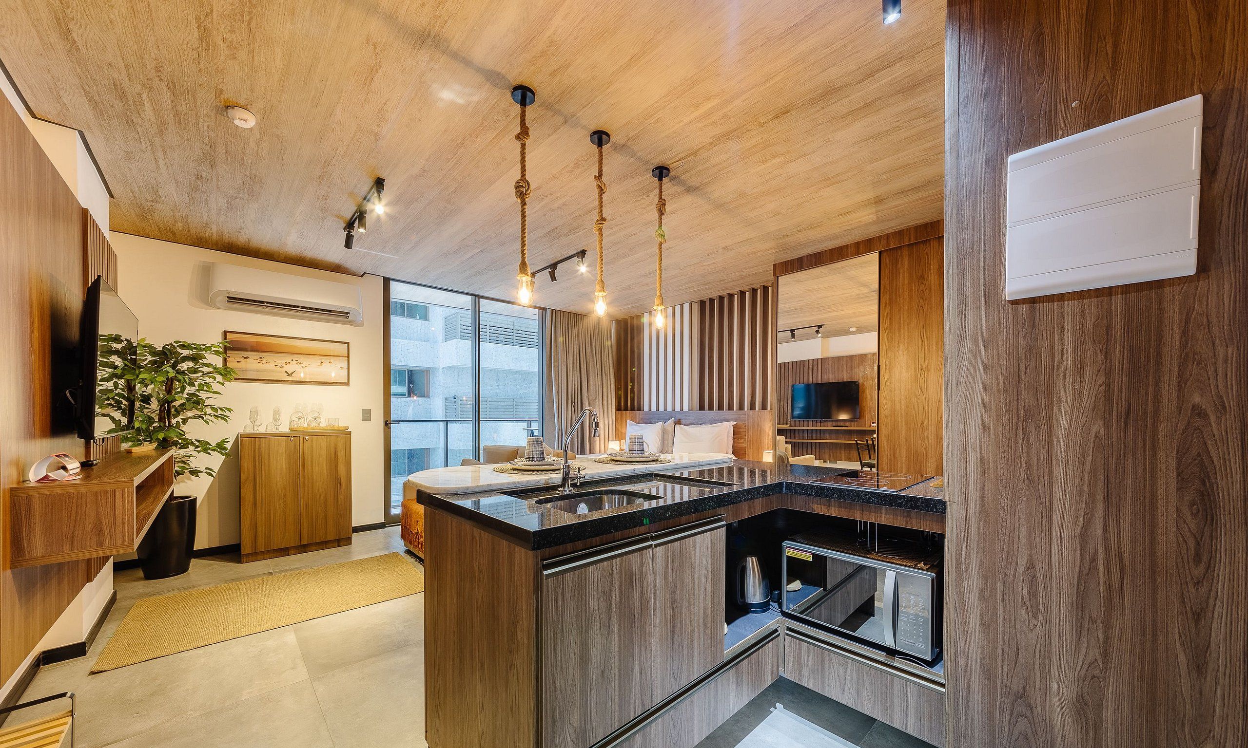 Una cocina moderna con una isla central, muebles de madera e iluminación colgante.