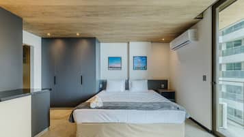 A modern hotel room with a bed, a wardrobe, a small bedside table, and a large window.