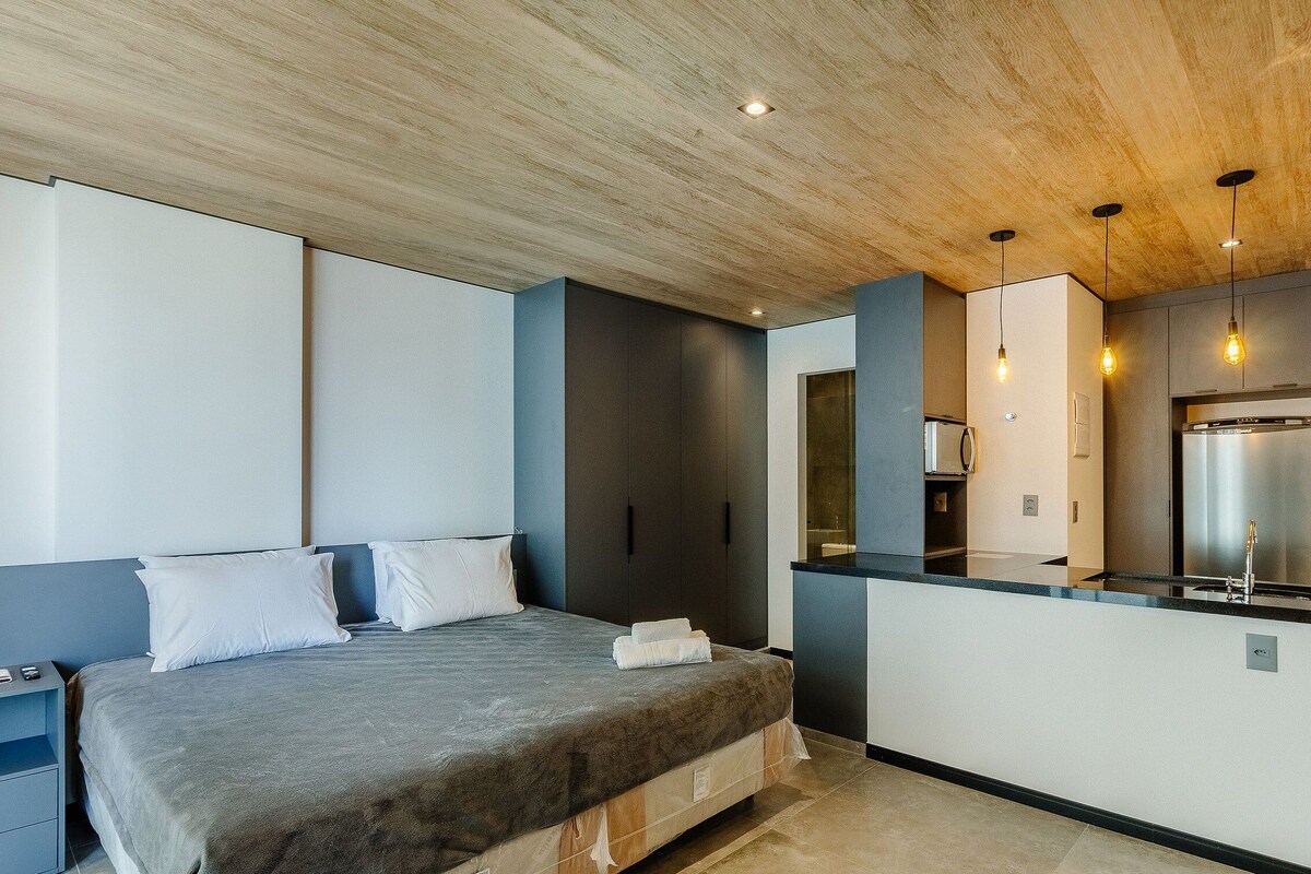 Ein modernes Schlafzimmer mit Bett, Einbauschrank, Küchenzeile und Badezimmer.