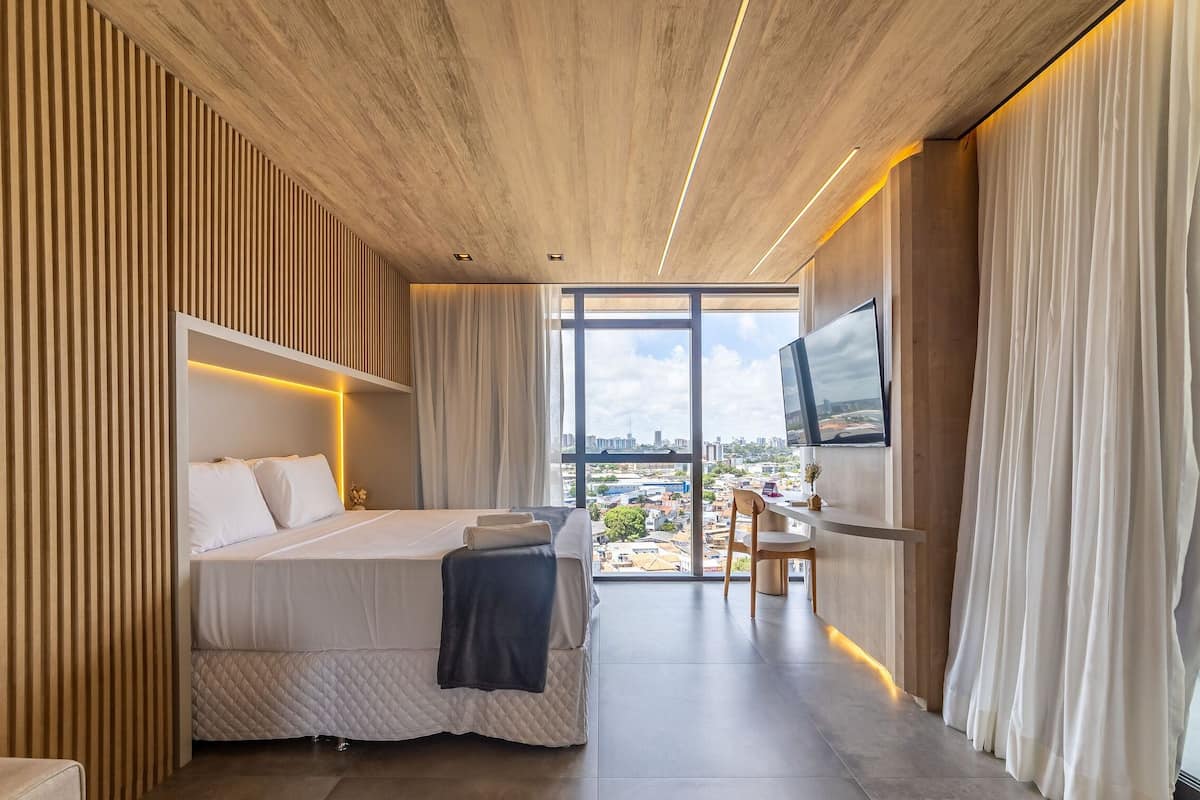 Une chambre d’hôtel moderne avec un grand lit, une télévision et une vue sur la ville.