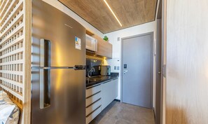 A compact kitchen with a stainless steel refrigerator, a built-in oven, and a sink. - NWTs - Estúdios com Vista Lateral Mar (Maceió)