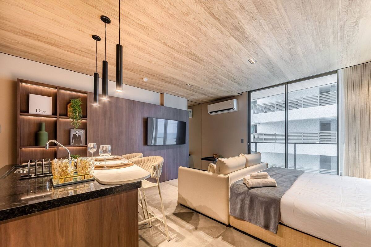 Une chambre d’hôtel moderne avec un plafond en bois, un grand lit, un canapé, une télévision et un mini-bar.