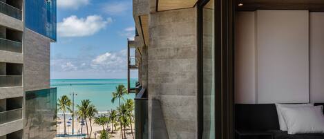 A modern hotel room with a view of the beach and ocean.