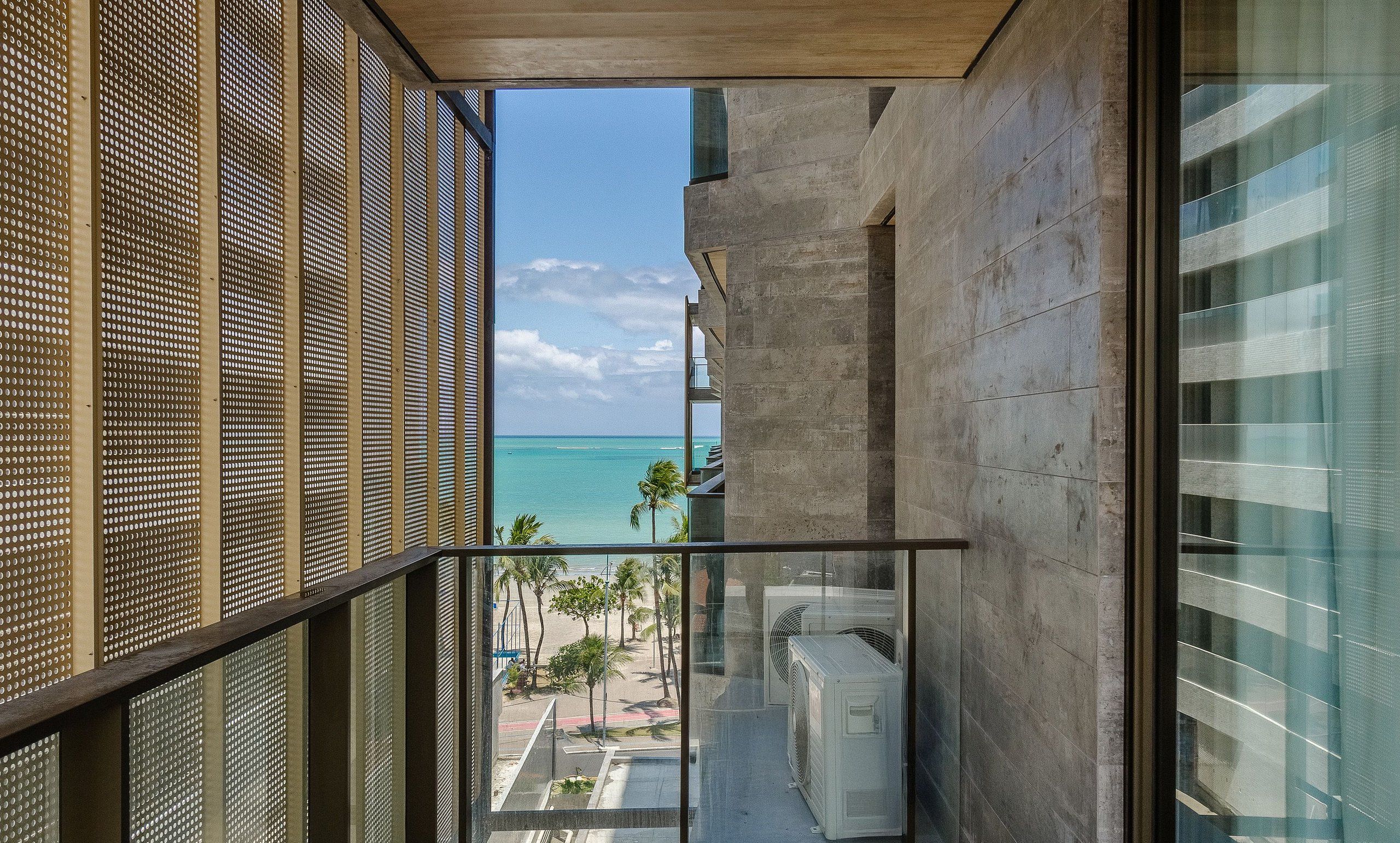 A balcony with a view of the ocean and palm trees.