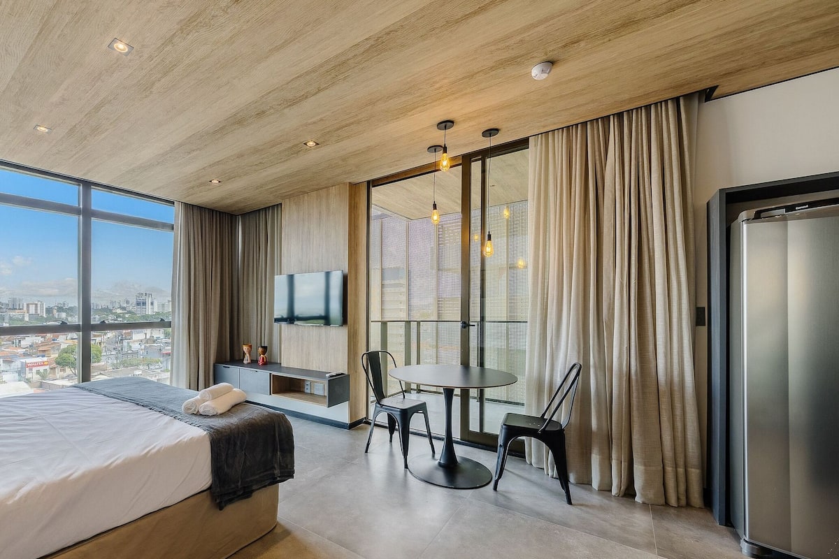 Une chambre d’hôtel moderne avec un grand lit, une table à manger et une vue sur la ville.