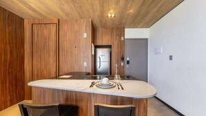 Eine moderne Küche mit einer zentralen Kochinsel, Holzvertäfelung an den Wänden und einem Edelstahlkühlschrank.