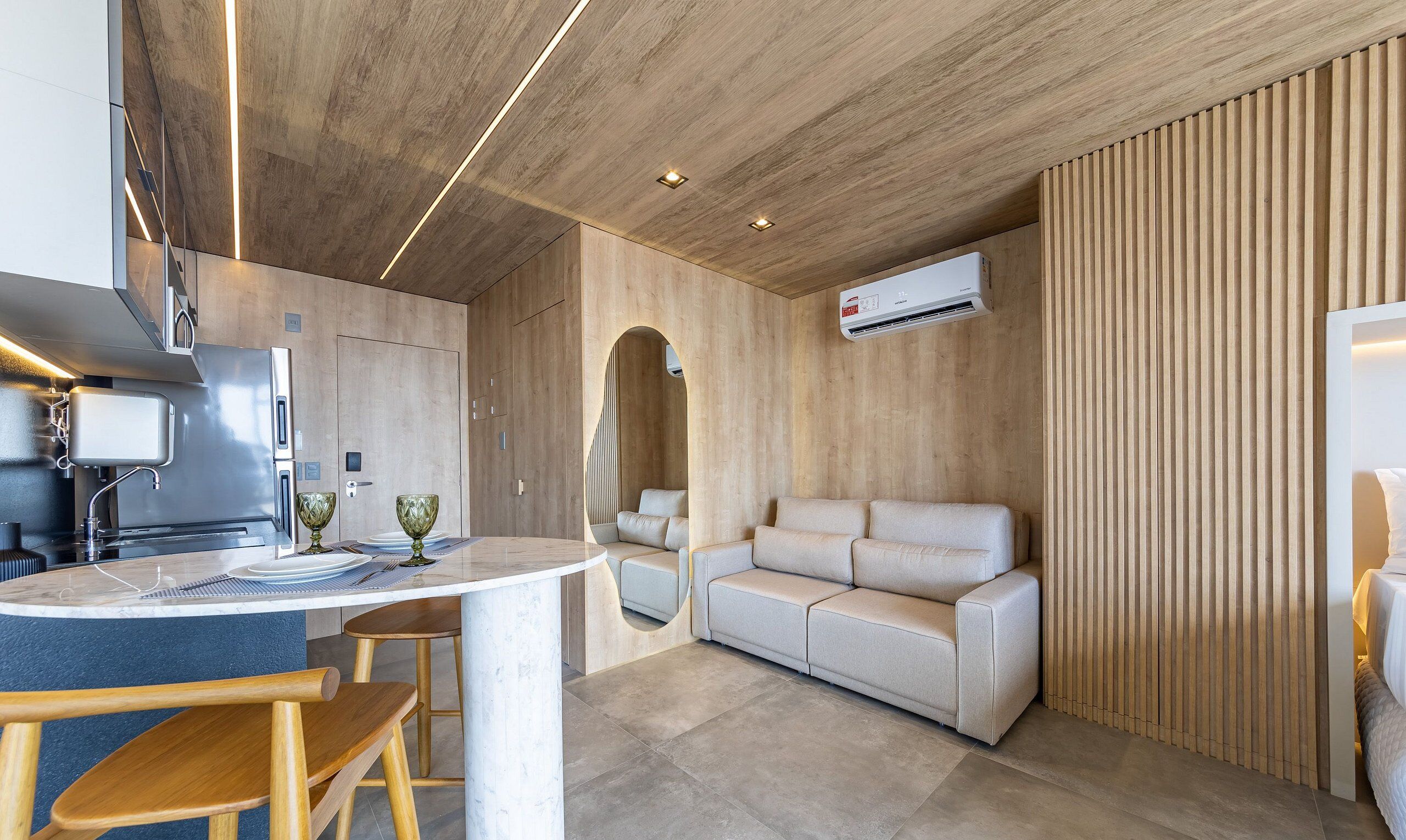 A modern kitchen with a built-in stove, a dining area with a marble table, and a sofa.