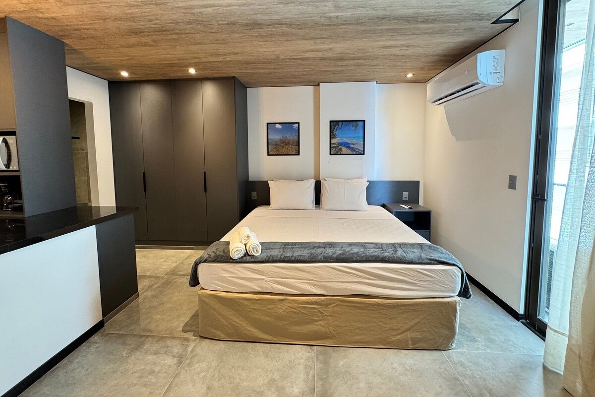 Ein modernes Schlafzimmer mit Bett, Nachttisch, Schreibtisch und einem großen Fenster.