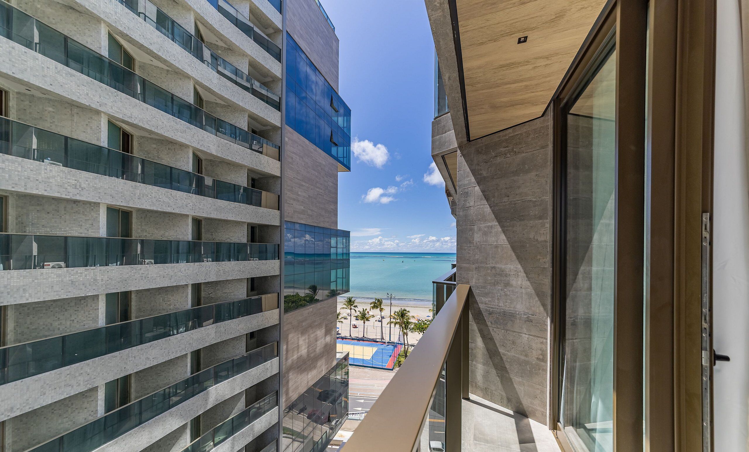 A high-rise hotel with multiple balconies overlooking a beach.