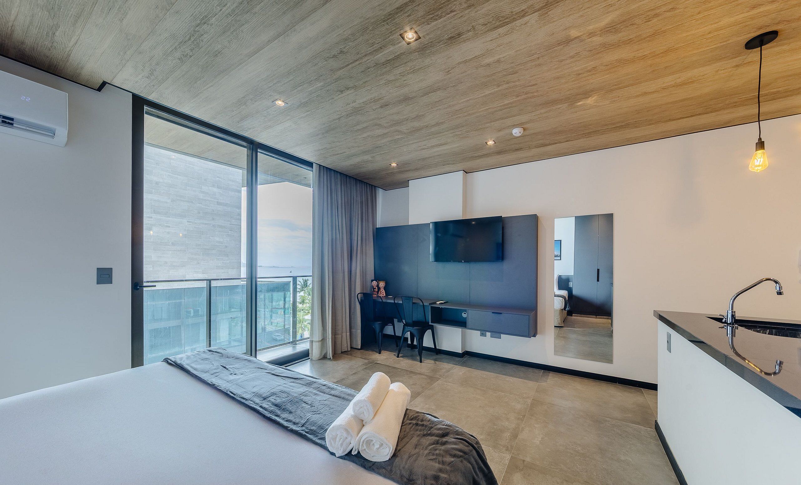 A modern bedroom with a large bed, a desk, and a TV.