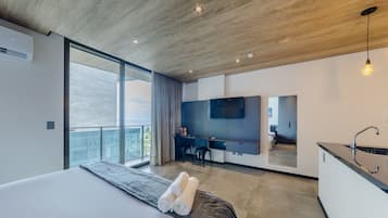 A modern bedroom with a large bed, a desk, and a TV.