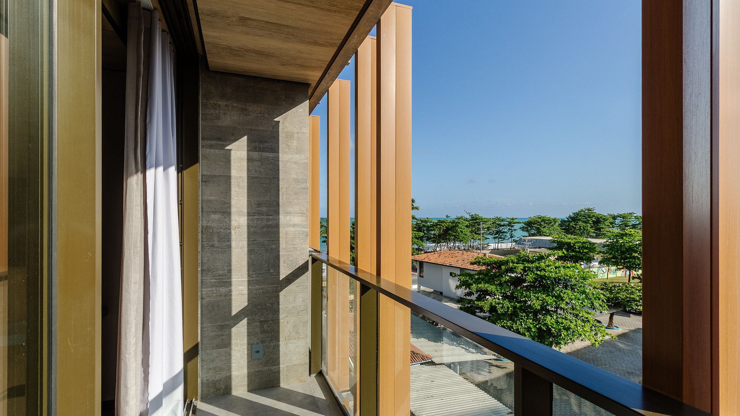 A balcony with a view of a residential area, including houses and trees.