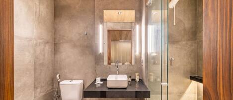A modern bathroom with a glass shower enclosure, a white toilet, and a black countertop with a sink.