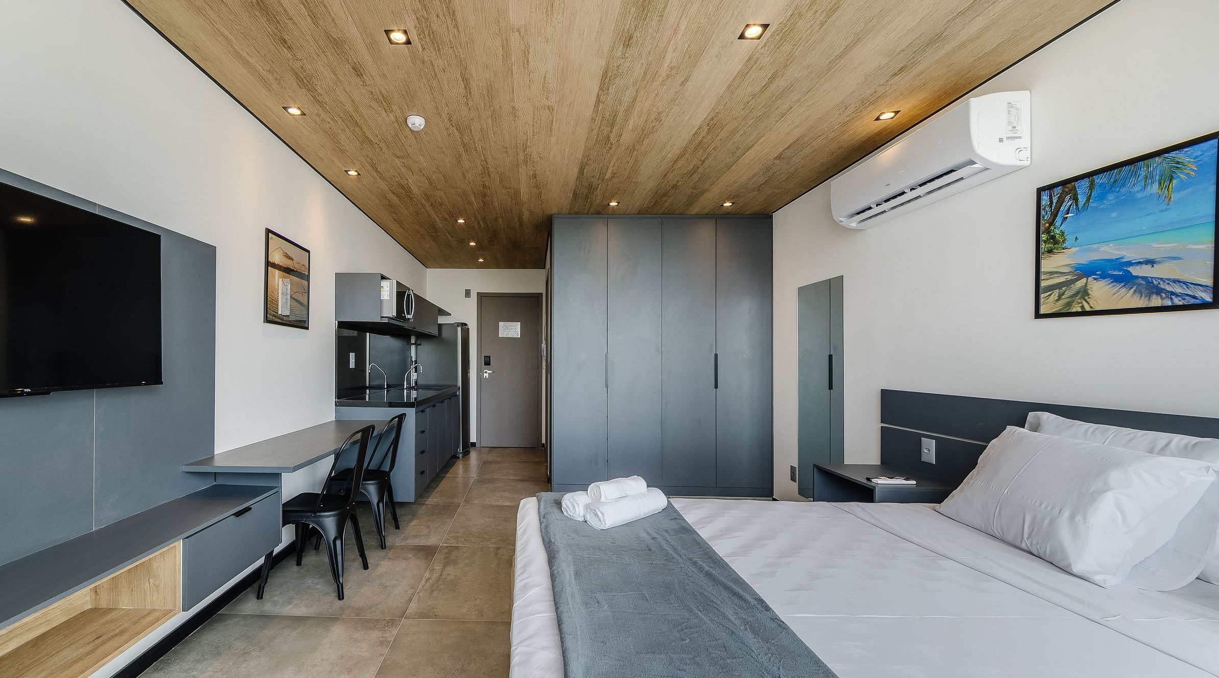 A modern hotel room with a bed, a desk, and a TV.