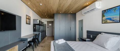 A modern hotel room with a bed, a desk, and a TV.