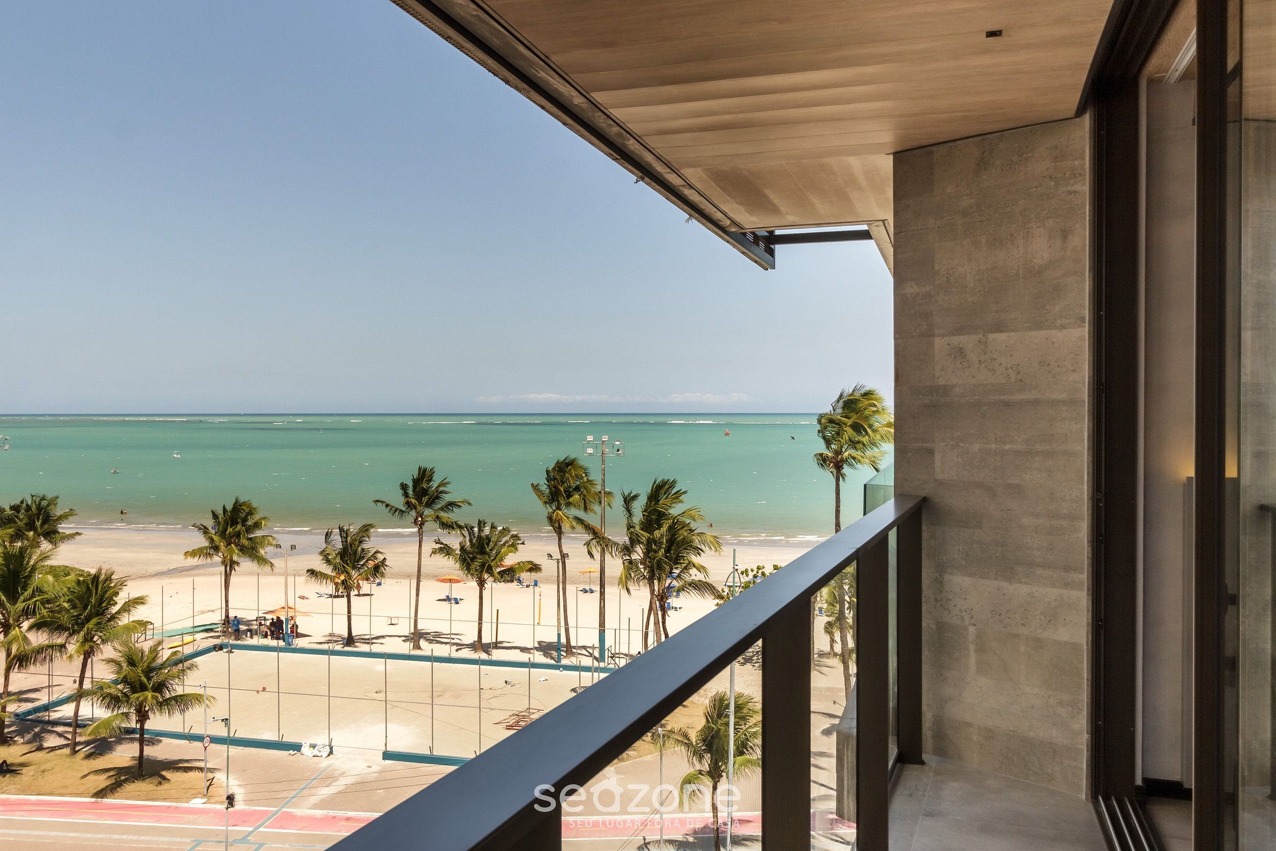Ein Balkon mit Blick auf einen Strand, Palmen und den Ozean.