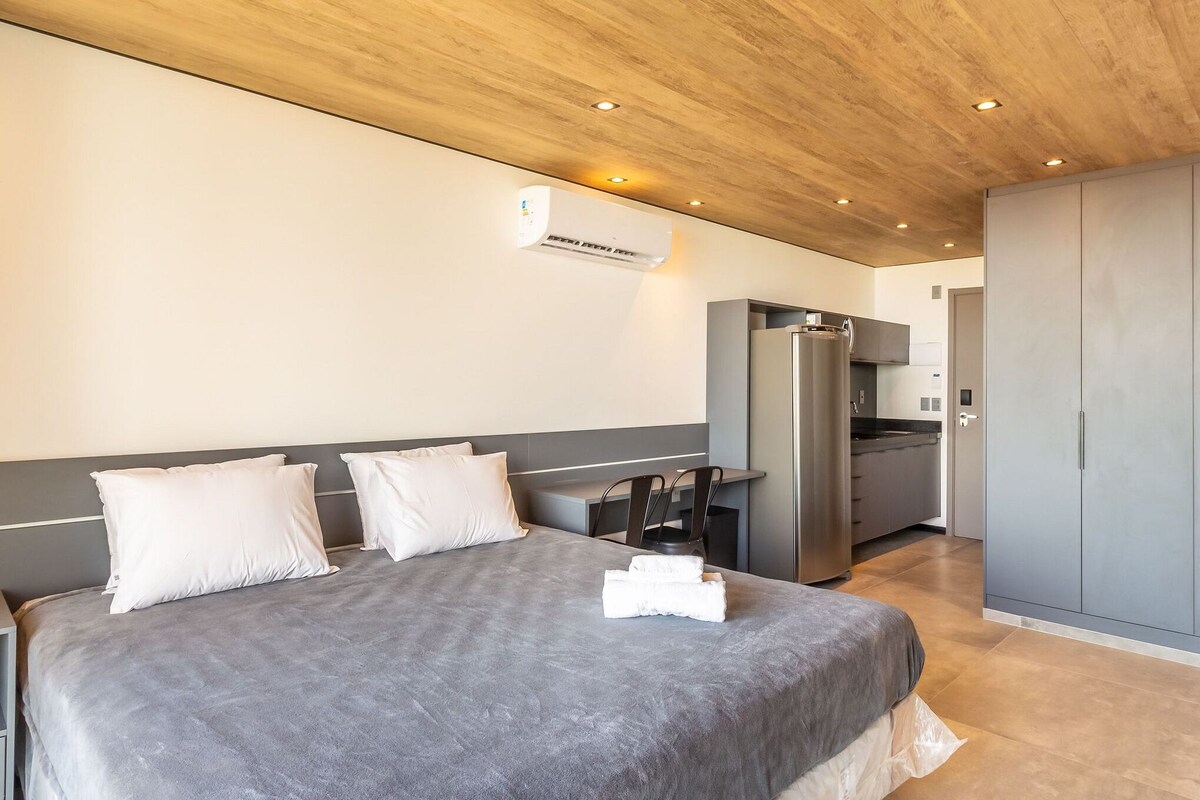 Ein Hotelzimmer mit Bett, Schreibtisch, Küchenzeile und Kleiderschrank.