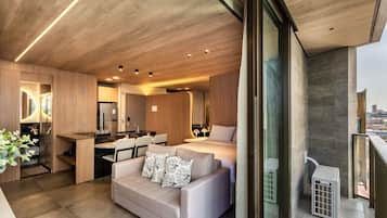 A modern interior with a kitchen, dining area, and a living space with a sofa and a bed.