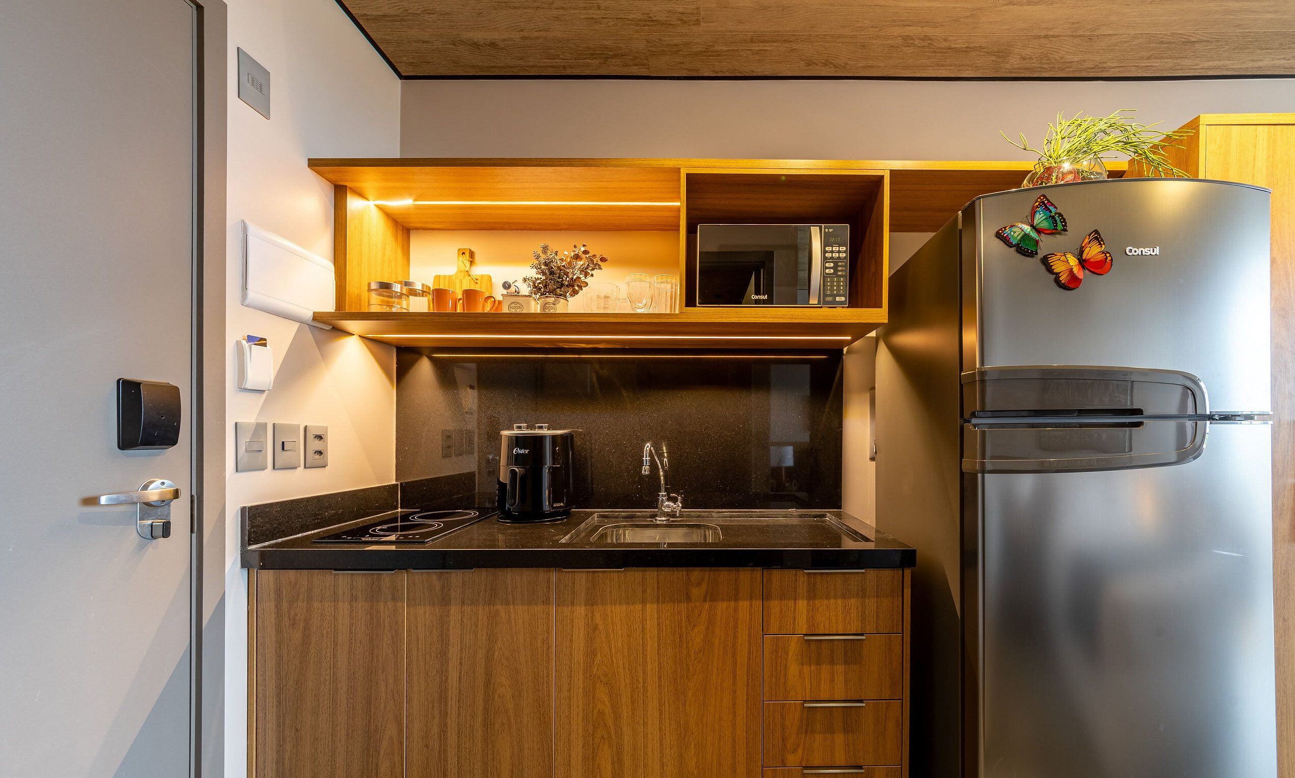 A modern kitchen with wooden cabinets, a stainless steel refrigerator, a microwave, and a coffee maker.