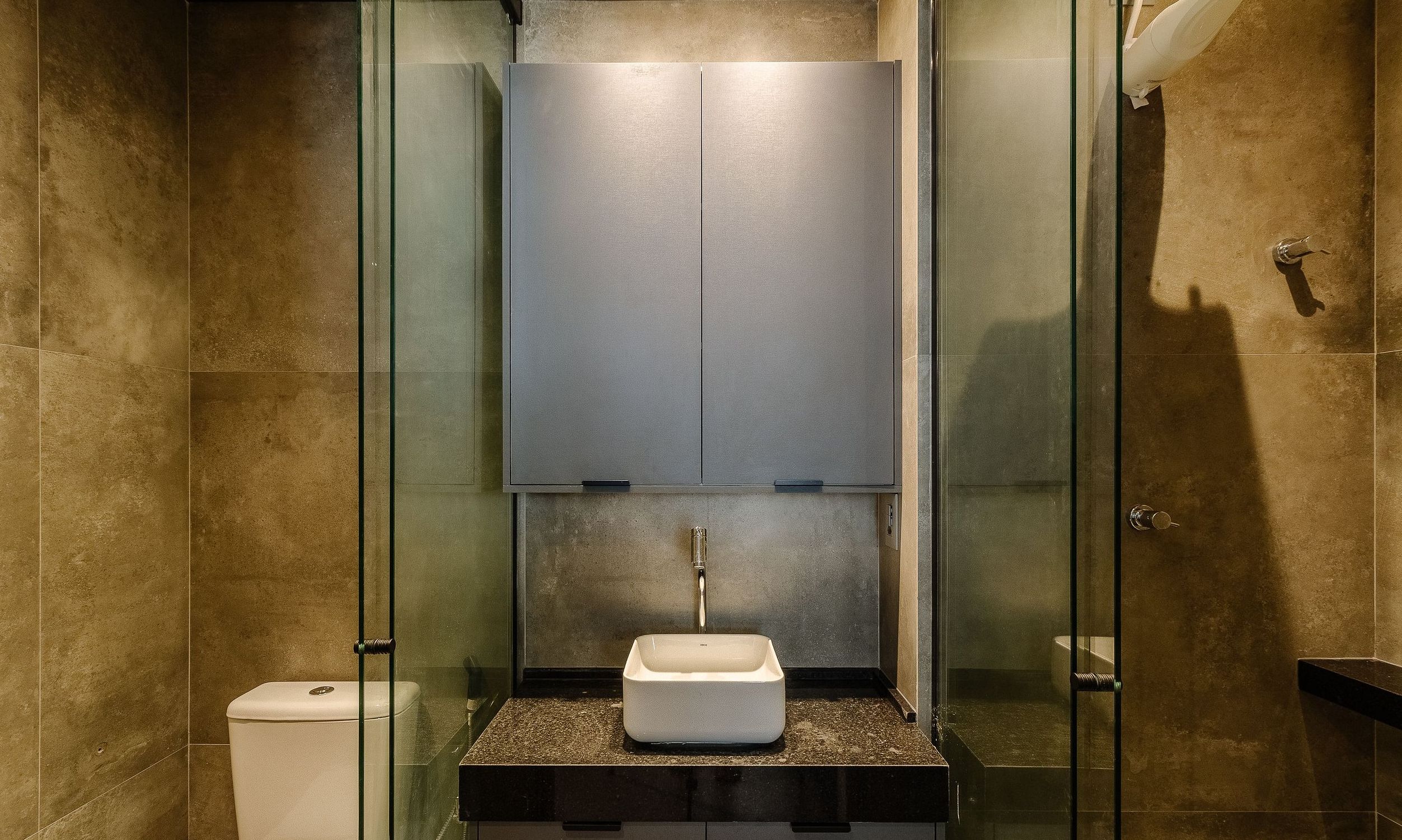 A modern bathroom with a glass-enclosed shower, a white pedestal sink, and a large mirror above the sink.