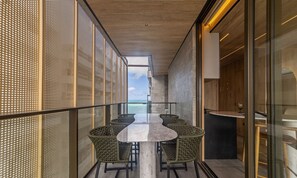 A modern interior with a long dining table and wicker chairs, a view of the sea, and a balcony with a railing. - NWTs - Estúdios com Vista Lateral Mar (Maceió)