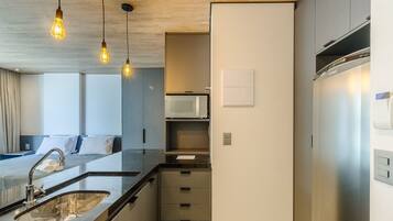 Una cocina moderna con microondas integrado, refrigerador de acero inoxidable y una encimera con lavamanos.