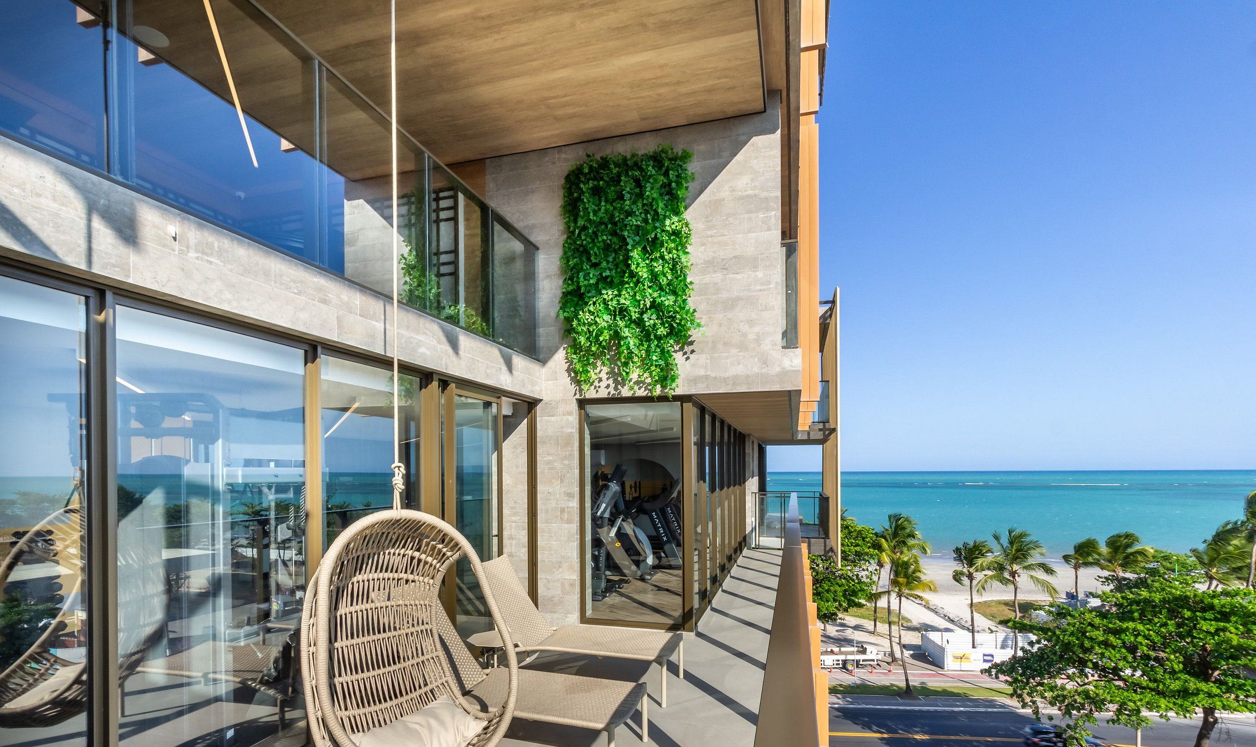 Un edificio moderno con balcón de vidrio con vista a la playa.