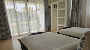Une chambre d’hôtel avec deux lits, une armoire et une vue sur l’extérieur.