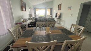 Zona pranzo con tavolo apparecchiato per quattro persone, ventilatore a soffitto e vista sul soggiorno.