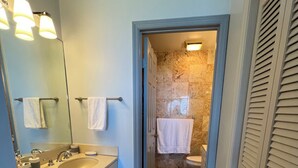 Un bagno con doppio lavabo, uno specchio e zona doccia.