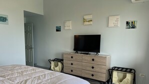 Una camera da letto con un letto, una cassettiera, una TV e opere d'arte alle pareti.