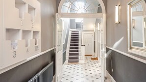 Un pasillo con una escalera, un radiador y una puerta que da a otra habitación.