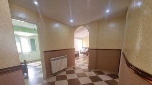 A hallway with a checkered floor, a radiator, and a door leading to another room. - Large Apartment F5 & Large Terrace Sea View (Dellys)