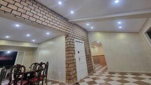 A dining area with a brick accent wall, a checkered floor, and recessed ceiling lights. - Large Apartment F5 & Large Terrace Sea View (Dellys)