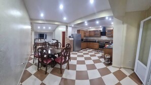 A dining area with a checkered floor, a round table, and wooden chairs. - Large Apartment F5 & Large Terrace Sea View (Dellys)