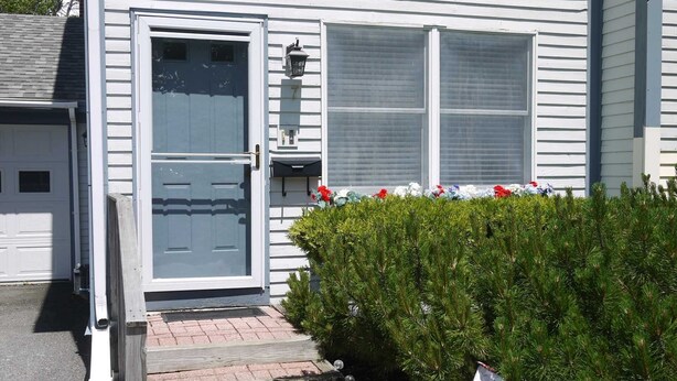 Una casa residencial con puerta principal, garaje y ventana con persianas.