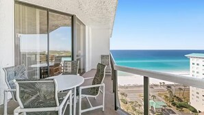 A balcony with a table and chairs, overlooking a beach and ocean. - Surfside Resort #1508b (Miramar Beach)