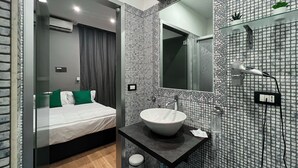 A modern bathroom with a mosaic tile backsplash, a large mirror, a sink, and a hairdryer. - Tiè tiè (Naples)